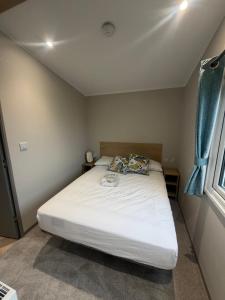 a bedroom with a white bed with blue curtains at The Elms Escape in Porthcawl