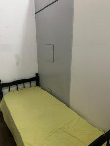 a small bedroom with a bed with a yellow sheet at Dormitório in Uberlândia