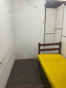 a yellow bench sitting in a corner of a room at Dormitório in Uberlândia