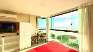 a bedroom with a large window with a view of the ocean at Studios Praia Grande - VISTA MAR in Arraial do Cabo