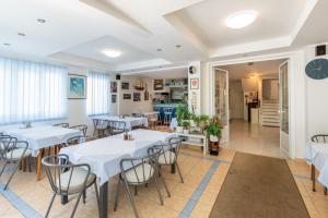 a restaurant with white tables and chairs and a hallway at K&D Home in Rab