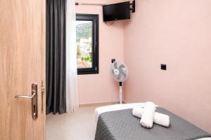 a room with a bed with a fan and a window at Swan Paradise Tolo in Tolo
