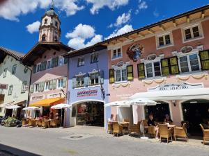 a building with a clock tower with tables and umbrellas at Gästehaus La Puccia in Mittenwald