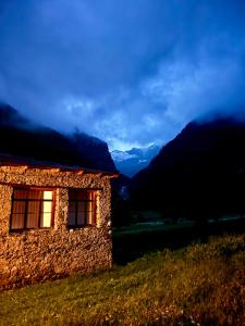 a building on a hill with mountains in the background at Madisha's Guesthouse in Mestia +13 photos