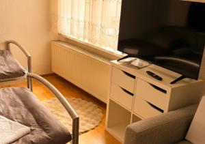 a living room with a tv on a white dresser at Harzer Domschatz-Auszeit Monteure - Einzelbetten in Halberstadt