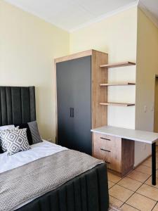 a bedroom with a bed and a desk and shelves at Airport Urban Studio in Benoni
