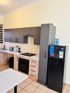 a kitchen with a black refrigerator and a table at Airport Urban Studio in Benoni
