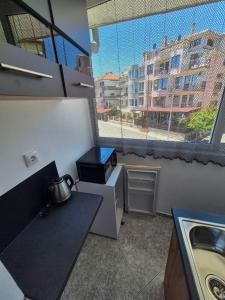 a kitchen with a sink and a large window at Къща за гости Баврия in Ravda