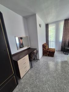a living room with a tv on a desk and a chair at Къща за гости Баврия in Ravda