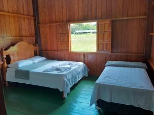 a bedroom with two beds and a window at Amazon Anavilhanas Lodge in Aiparuça