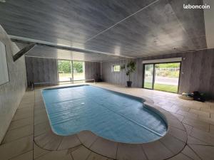 a large swimming pool in a room with a ceiling at Gîte Le petit Fresnay in Le Bourgneuf-la-Forêt