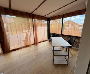 a dining room with a table and chairs and windows at Meublé de Tourisme Le Swing in Marsannay-la-Côte