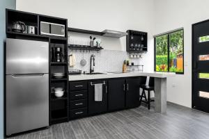 a kitchen with black cabinets and a stainless steel refrigerator at Villa Los Perezosos - Private Jacuzzi & Arenal Volcano View - La Fortuna in Fortuna
