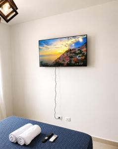 a flat screen tv hanging on a wall above a bed at Tropical Pearl Getaway in Los Paredones