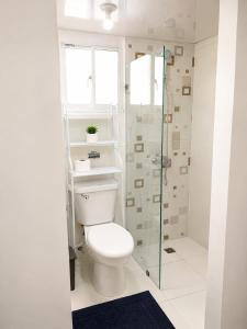 a bathroom with a toilet and a glass shower at Tropical Pearl Getaway in Los Paredones
