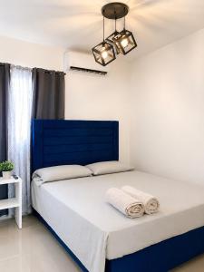 a bedroom with a blue bed with towels on it at Tropical Pearl Getaway in Los Paredones