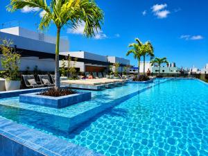 a swimming pool with palm trees on a building at Hit Cabo Branco by 123Quarto in João Pessoa +66 photos