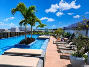 a pool on the roof of a building with chaises and palm trees at Hit Cabo Branco by 123Quarto in João Pessoa