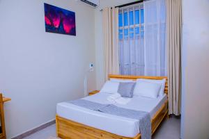 a small bedroom with a bed with a window at ExtraMile Apartments - 2BR-R in Dodoma
