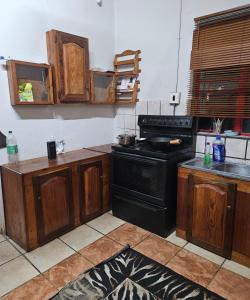a kitchen with a black stove and wooden cabinets at Blessed home by the Mountain surrounded macadamia in Barberton