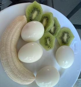 a white plate with a banana and kiwi and eggs at Pousada Maria Bonita - Centro, 10min da Praia de Camapum, Macau RN in Macau