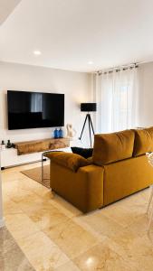 a living room with a brown couch and a flat screen tv at Aurah Home in Tudela