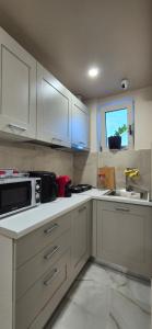 a kitchen with white cabinets and a sink and a microwave at Villa MarJon in Vlorë