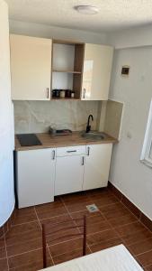 a kitchen with white cabinets and a sink at Apartmani Tajra in Donji Štoj