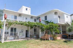 a white house with a tree in front of it at Apartmani Šarkinović in Sutomore