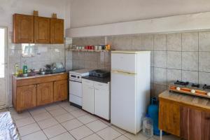 a kitchen with a white refrigerator and wooden cabinets at Apartmani Šarkinović in Sutomore +4 photos