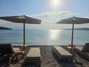 two chairs and umbrellas on a beach with the ocean at Magenta Beach in Porto Heli