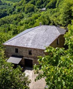 a large stone barn with a metal roof at Lar das louseiras in Rozabragada
