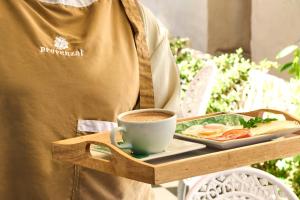 a man holding a tray of food and a cup of coffee at Casa Provenzal Hotel Boutique in Villa de Leyva