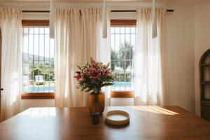 a vase of flowers on a wooden table in front of a window at Villa Pony in Calonge