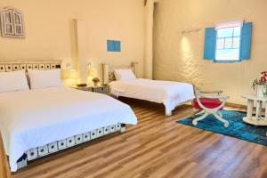 a room with two beds and a chair in it at Casa Provenzal Hotel Boutique in Villa de Leyva