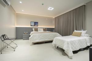 ein Hotelzimmer mit zwei Betten und einem Stuhl in der Unterkunft Duna Queen Hotel Conceito in Barreirinhas + 14 Fotos