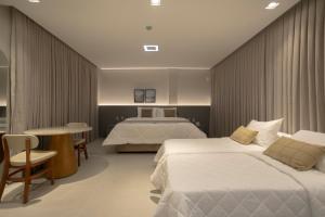 ein Hotelzimmer mit zwei Betten und einem Tisch in der Unterkunft Duna Queen Hotel Conceito in Barreirinhas