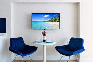 a table with two blue chairs and a tv on a wall at Casa Bellamare Batumi in Batumi