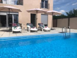 a swimming pool with chairs and umbrellas at Vila Komfor in Jajinci