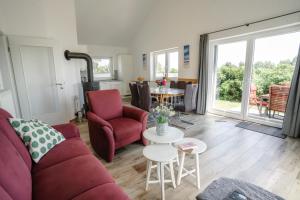 a living room with a red couch and a table at Haus JADEHUUS in Schweiburg