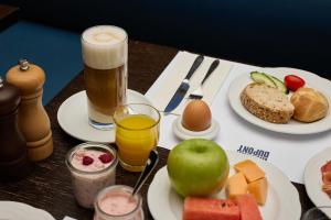 a table topped with plates of food and a glass of beer at Riverside Hotel Merian - opening 2026 in Basel