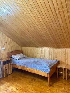 a bed in a wooden room with a wooden ceiling at TaVa House 2 in Yaremche