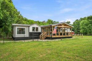 a tiny house with an american flag in a yard at Smallville Farm Retreat in Lake Catherine +21 photos