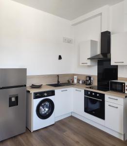 a kitchen with white cabinets and black appliances at Appartement Cévenol in Le Vigan +9 photos