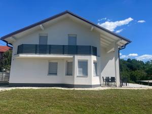 a white house with a balcony on top of a yard at Villa Vildana in Sarajevo