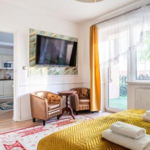a bedroom with a bed and two chairs and a television at Pensjonat Koral in Kołobrzeg