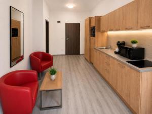 a room with a kitchen with a red chair and a counter at M14 Stay Cluj in Cluj-Napoca