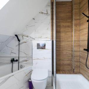 a bathroom with a toilet and a bath tub at Pensjonat Koral in Kołobrzeg +80 photos