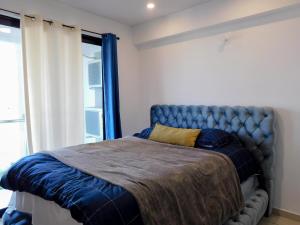 a bedroom with a bed with a blue head board at Bostor Apartament in San Salvador