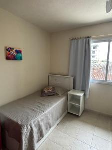 a small bedroom with a bed and a window at Sobrado confortável a uma quadra do mar. in Matinhos